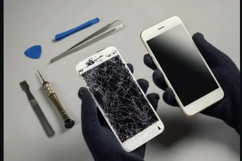 Pantalla de móvil rota junto a herramientas de reparación